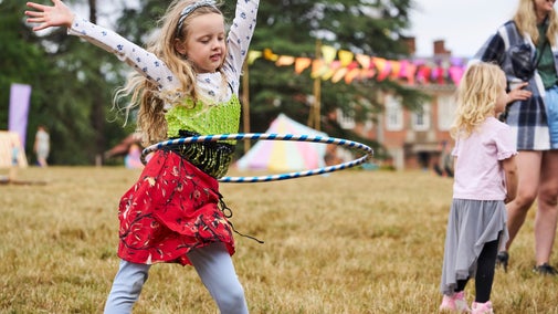 A girl dancing with a hula hoop in the Summer of Play field at Hanbury Hall